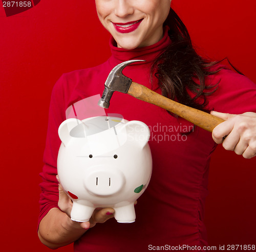 Image of Smiling Woman in Red Holds Hammer Above Piggy Bank Savings