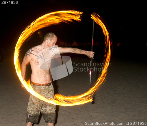 Image of Shirtless Man on Beach Spins Burning Rod Playing with Fire