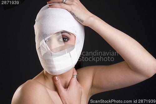 Image of Woman Wrapped in White Gauze Holding Head INjury