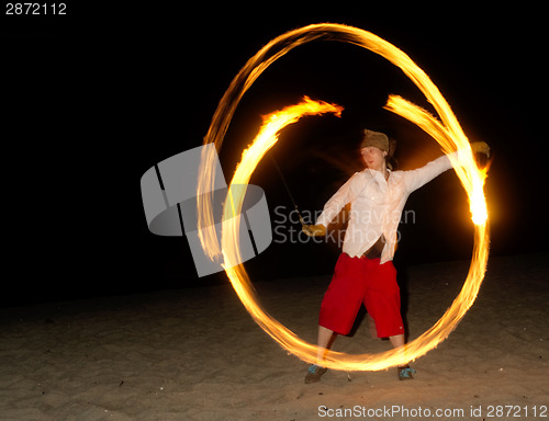 Image of Man on Beach Spins Burning Chains Playing with Fire