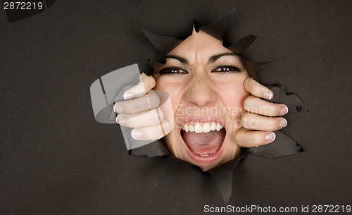 Image of Pretty Female Face Breaking In Through Black Paper