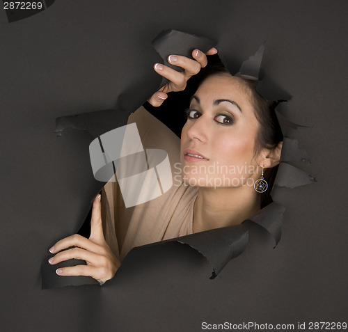 Image of Beautiful Brunette Woman Looks Sideways Through Torn Hole