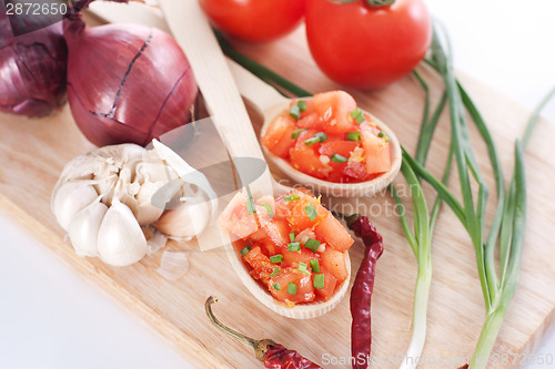 Image of Salsa in two spoons on a wooden board and ingredients