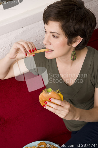 Image of Woman Eating Burger Fries Lunch Sofa Living Room Meal Time