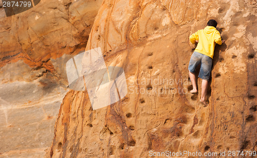 Image of Young Boy Climbs Sandstone Rock Wall Beach Front Male Climber