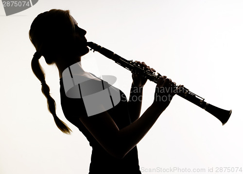 Image of Female Musician in Silhouette Practices Woodwind Technique on Cl
