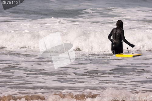 Image of Young Woman Female Wake Board Rider Wades out Sea Surf