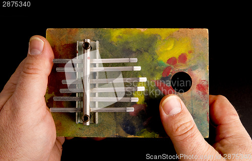 Image of Hands Playing Tune on Musical Instrument of the Thumb Harp