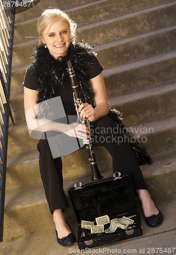Image of Female Street Performer Sits on Steps Clarinet Case With Tips