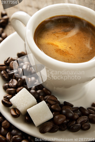 Image of Small cup of black coffee on a brown background with coffee bean