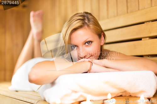 Image of Lady relaxing in traditional wooden sauna.