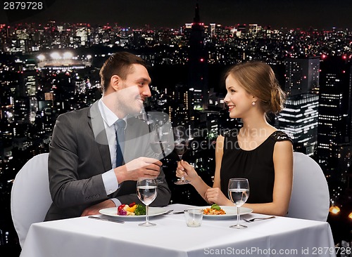 Image of smiling couple eating main course at restaurant