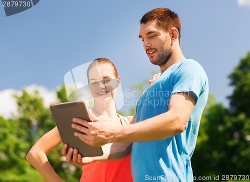 Image of smiling couple with tablet pc outdoors
