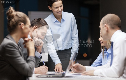 Image of smiling female boss talking to business team