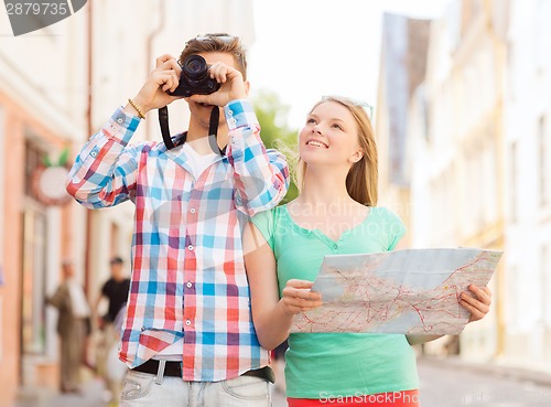 Image of smiling couple with map and photo camera in city