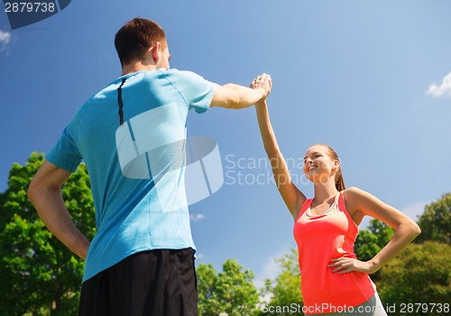 Image of two smiling people making high five outdoors