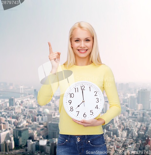 Image of student with wall clock and finger up