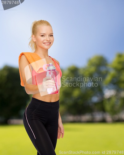 Image of smiling sporty woman with water bottle and towel