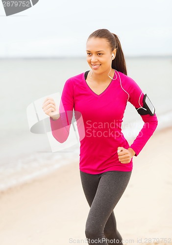 Image of smiling young woman running outdoors