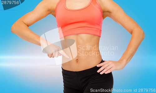 Image of close up of woman pointing finger at her six pack