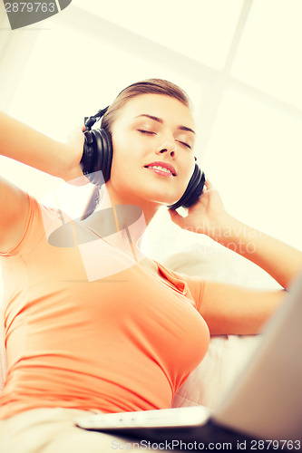 Image of woman with headphones and laptop at home