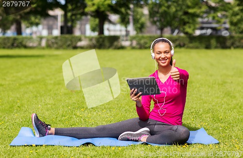 Image of smiling woman with tablet pc outdoors