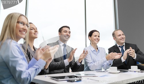 Image of business team with laptop clapping hands