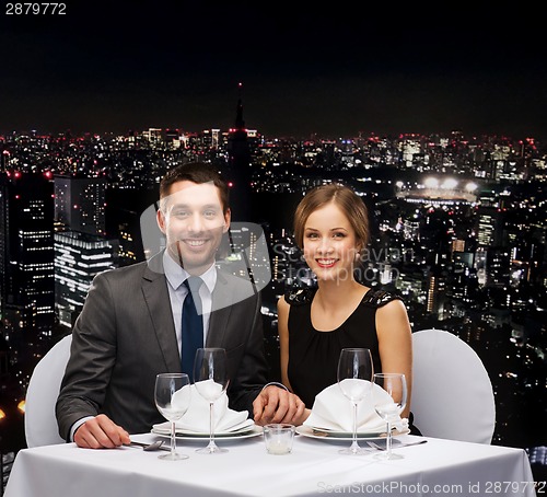Image of smiling couple holding hands at restaurant