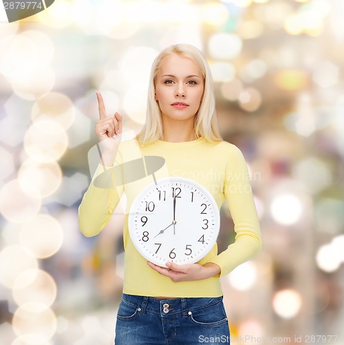 Image of student with wall clock and finger up