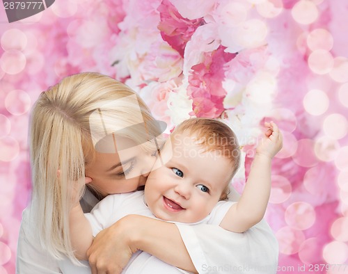 Image of happy mother kissing smiling baby