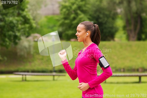 Image of smiling young woman running outdoors