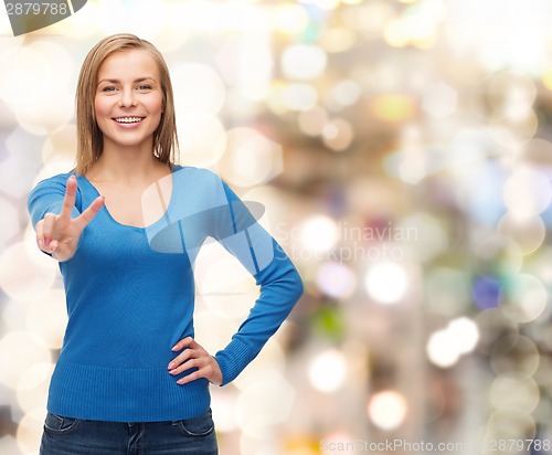 Image of smiling teenage girl showing v-sign with hand