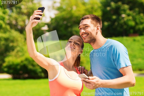Image of two smiling people with smartphones outdoors