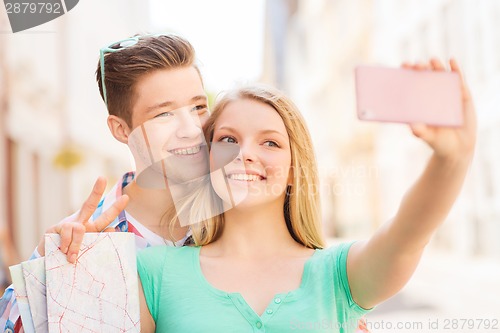 Image of smiling couple with smartphone in city