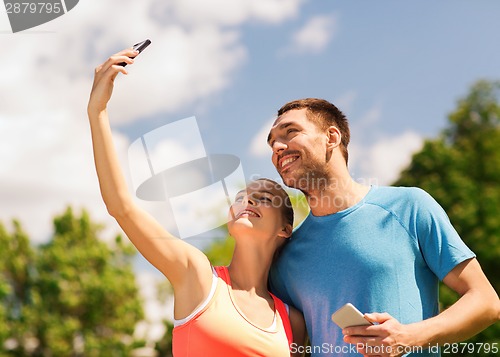 Image of two smiling people with smartphones outdoors