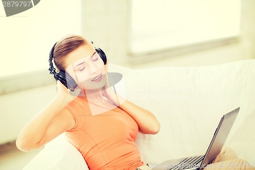 Image of woman with headphones and laptop at home