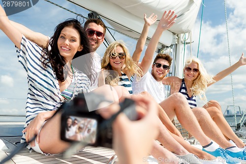 Image of smiling friends photographing on yacht