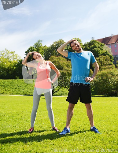 Image of smiling couple stretching outdoors