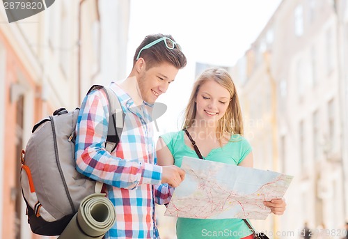 Image of smiling couple with map and backpack in city