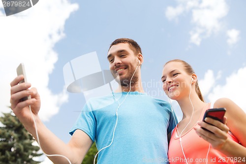 Image of two smiling people with smartphones outdoors