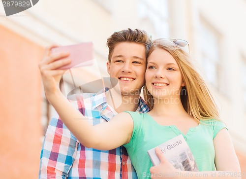 Image of smiling couple with smartphone in city