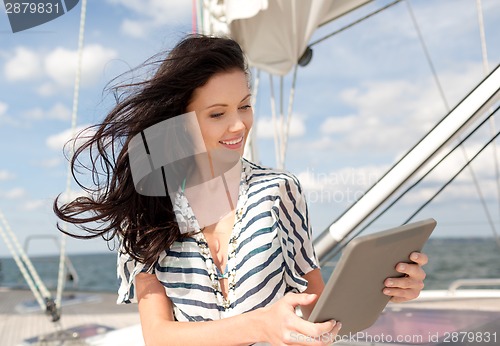 Image of smiling woman sitting on yacht with tablet pc