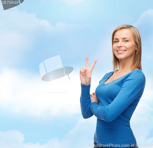 Image of smiling teenage girl showing v-sign with hand