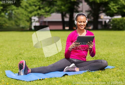 Image of smiling woman with tablet pc outdoors