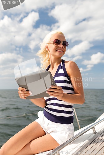 Image of smiling woman sitting on yacht with tablet pc