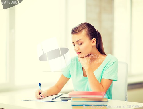 Image of tired student writing in notebook