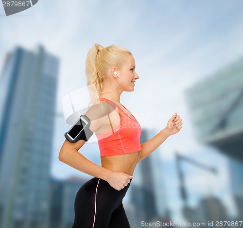 Image of sporty woman running with smartphone and earphones