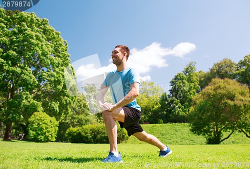 Image of smiling man stretching outdoors