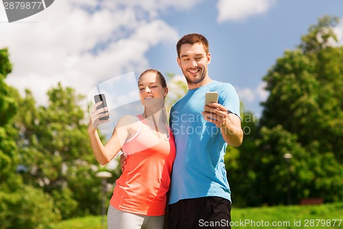 Image of two smiling people with smartphones outdoors
