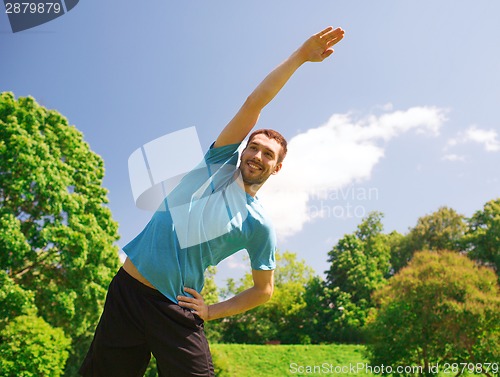 Image of smiling man stretching outdoors